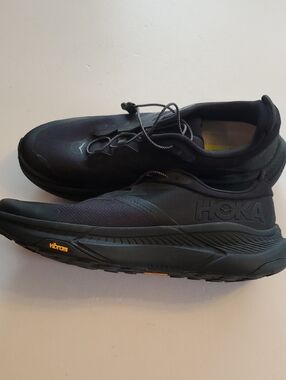 Hoka Transport Black Running Sneakers with Yellow Vibram Accents.